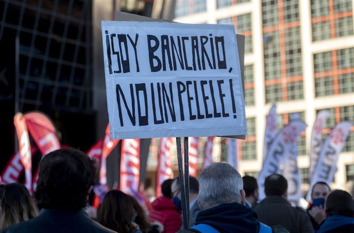 Una persona perteneciente a la plantilla de CaixaBank sostiene una pancarta durante una manifestación frente a las Torres Kio, a 22 de febrero de 2022, en Madrid (España).