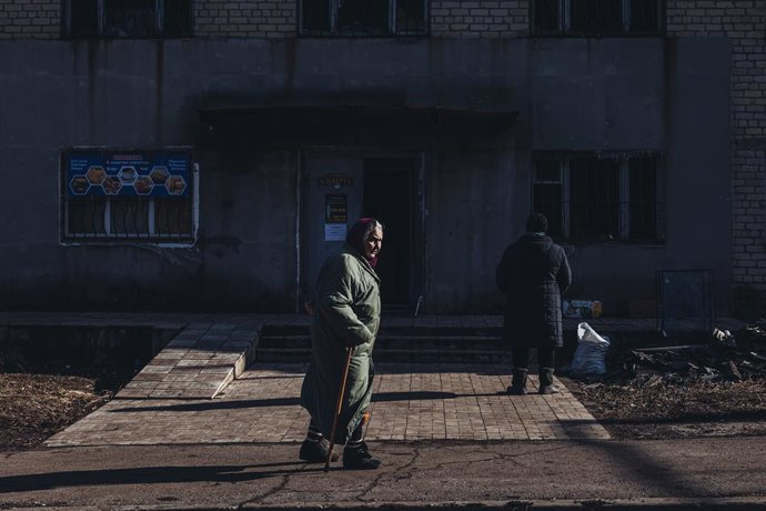 Una dona gran camina per davant d'un edifici bombardejat, a 23 de febrer de 2022, a Novoluhans'ke, Oblast de Donetsk (Ucrana).