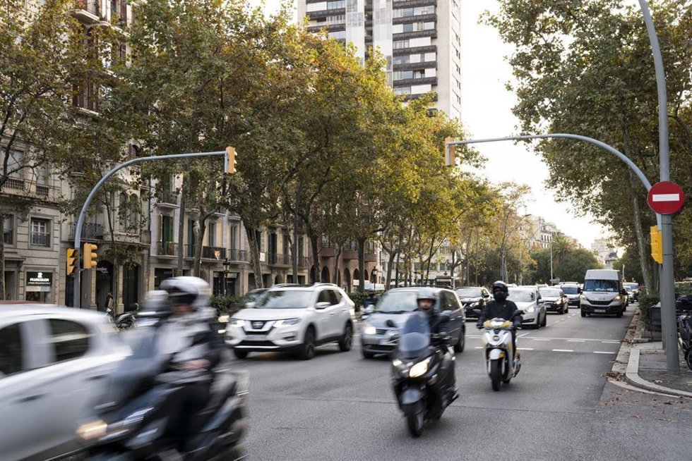 Coches y motos circulan por una calle de Barcelona con tráfico.