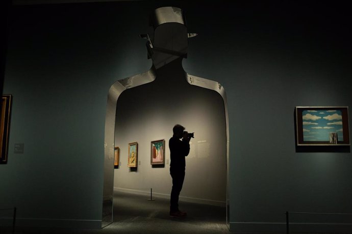 Una persona graba con su cámara de vídeo en la presentación de la exposición  'La máquina Magritte', en CaixaForum, a 24 de febrero de 2022, en Barcelona