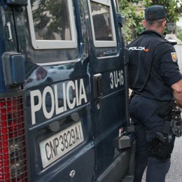 Archivo - Un agente de la Policía Nacional, junto a un vehículo del cuerpo.