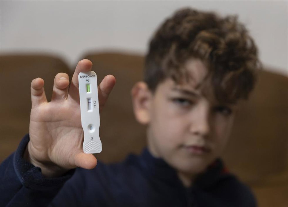 Archivo - Un niño enseña un test de antígenos.