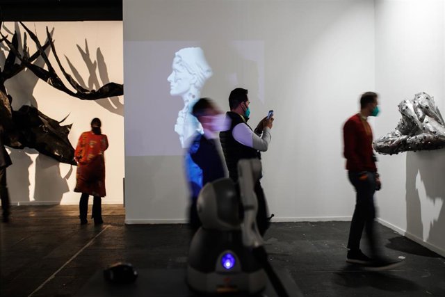 Varios visitantes junto a la obra, NFT 'Autorretrato Háptico', de la artista Amparo Sard, en el estand de la galería Baró, en ARCO 2022, a 23 de febrero de 2022, en Madrid (España) . NFT son las siglas de Non Fungible Tokens, Tokens no fungibles, en caste