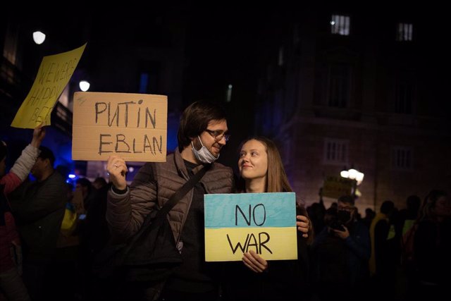Varias personas sostienen pancartas en una concentración ante la embajada rusa en Barcelona tras los primeros ataques rusos registrados en Ucrania esta pasada madrugada, a 24 de febrero de 2022