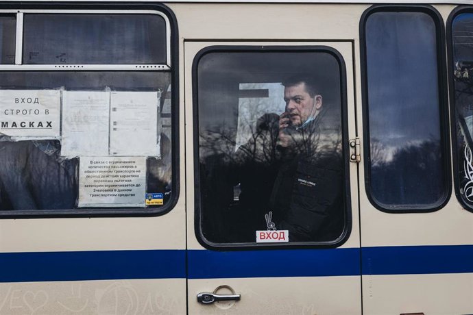 Un hombre mira desde un autobús que lleva a desplazados del Donbass hacia el oeste del país, a 24 de febrero de 2022, en Ucrania. Las autoridades de Ucrania han confirmado este jueves la muerte de cerca de 40 personas, entre ellos diez civiles, a consec