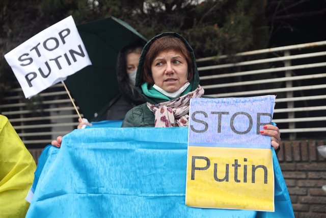 Una mujer con una bandera de Ucrania y carteles parar parar a Putin, participan en una nueva concentración ante la embajada rusa de Madrid tras los ataques en Ucrania, a 25 de febrero de 2022