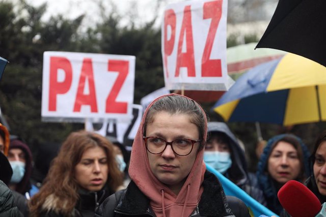 Una mujer con un paraguas de la bandera de Ucrania, participa en una nueva concentración ante la embajada rusa de Madrid tras los ataques en Ucrania, a 25 de febrero de 2022, en Madrid (España). Los participantes protestan por los ataques registrados desd