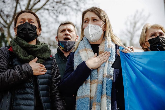 Varias personas cantan el himno de su país una concentración ante la embajada rusa en Madrid.