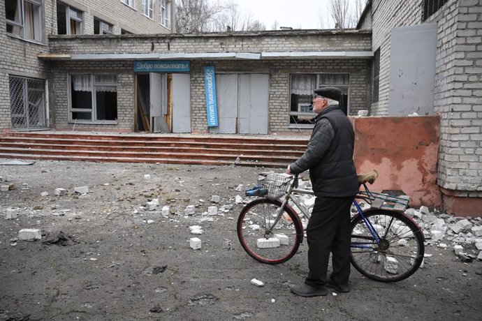 Un home mira les runes d'un collegi en Donetsk en el segon dia de la invasió russa. 