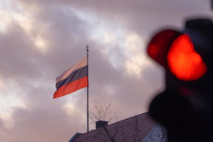 24 February 2022, Berlin: The flag of the Russian Embassy flies in front of a red traffic light in the early morning. The Russian army entered Ukraine in the early morning. Photo: Joerg Carstensen/dpa