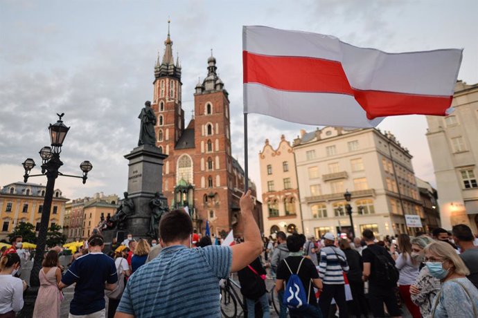 Archivo - 15 August 2020, Poland, Krakow: A protester is seen raising a white-red-white Belarusian opposition flag during a demonstration by the Belarusians in Poland, against Belarusian President Alexander Lukashenko and what they called an electoral f