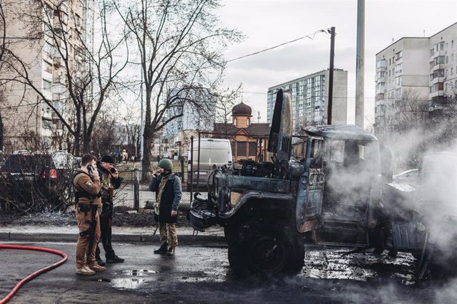 Varios soldados del ejercito ucraniano observan el vehículo militar de su ejército calcinado, a 25 de febrero de 2022, en Kiev (Ucrania). 