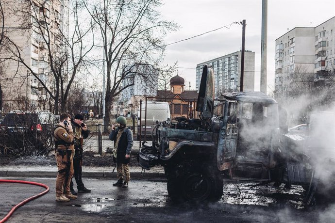 Varios soldados del ejercito ucraniano observan el vehículo militar de su ejército calcinado, a 25 de febrero de 2022, en Kiev (Ucrania). Los soldados rusos han entrado en Kiev para realizar combates en varios puntos del país. Rusia ha pedido que Ucrani