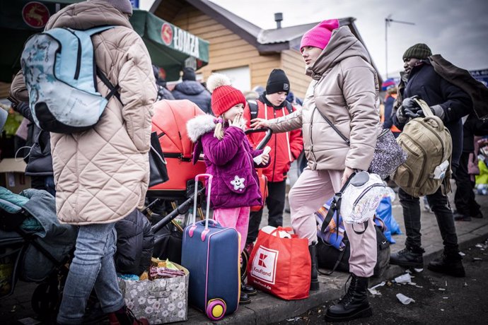 27 February 2022, Poland, Przemysl: Ukrainian Krystyna Krajnik waits with her children Alla and Svyatoslav for their onward transport after crossing the border from Shehyni in Ukraine to Medyka in Poland. Many Ukrainians leave the country after military