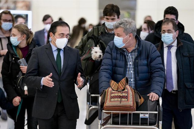 El ministro de Asuntos Exteriores, Unión Europea y Cooperación, José Manuel Albares (i), conversa con varios españoles repatriados a su llegada al Aeropuerto Adolfo Suárez Madrid Barajas, a 28 de febrero de 2022, en Madrid (España). 