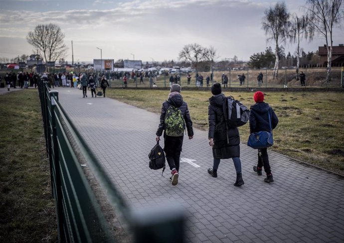 26 February 2022, Poland, Przemysl: Refugees from Ukraine walk through the Polish border area after crossing the border in Poland. Many Ukrainians leave the country after military actions of Russia on Ukrainian territory. Photo: Michael Kappeler/dpa