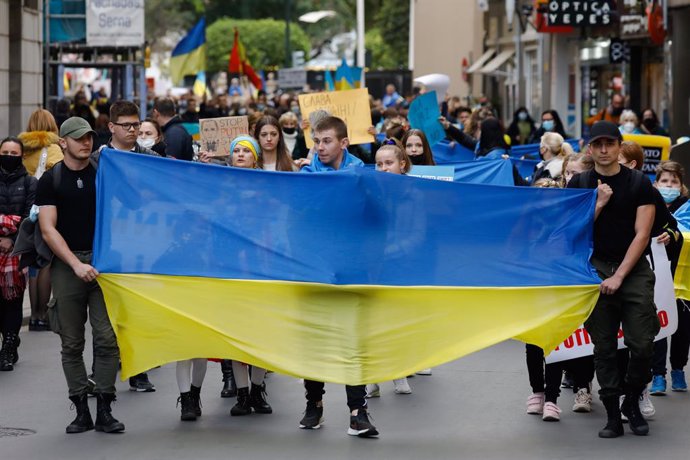 Varios jóvenes con una bandera de Ucrania, participan en una segunda concentración para apoyar a Ucrania tras los ataques recibidos por parte de Rusia, en la plaza de la Cruz Roja de Murcia, a 25 de febrero de 2022, en Murcia (España). Los participantes