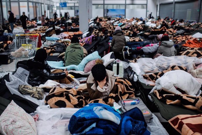 Varias personas descansan en un centro comercial destinado a la acogida temporal de los refugiados que vienen a Polonia en  búsqueda de refugio, a 28 de febrero de 2022, en Mylny (Polonia). Los ucranianos tardan entre dos o tres días en conseguir llegar
