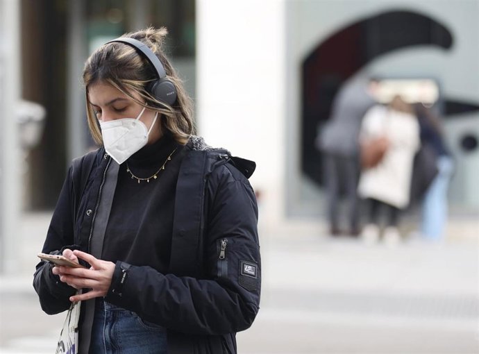 Una mujer camina por la calle con mascarilla.