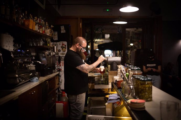 Archivo - Un camarero sirve una cerveza en el interior de un bar 