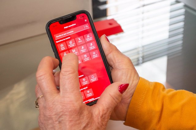 Una persona mayor utiliza una aplicación bancaria en un teléfono móvil
