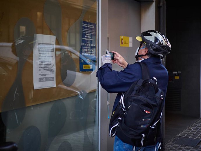 Archivo - Un hombre saca una foto a un anuncio en una oficinas de empleo en Pamplona.