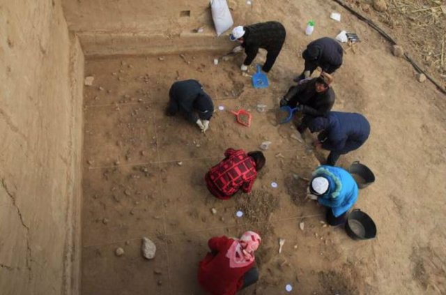 Arqueólogos excavando la superficie bien conservada en el sitio de Xiamabei, en el norte de China, mostrando herramientas de piedra, fósiles, ocre y pigmentos rojos.