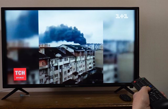 24 February 2022, Ukraine, Kiev: A person points the remote at a television screen showing news reports on the shelling of the airport in Ivano-Frankivsk in thde wake of the Russian invasion of Ukraine. Photo: Igor Golovniov/SOPA Images via ZUMA Press Wir