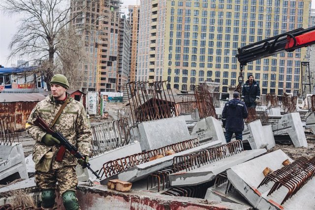 Dos operarios levantan losas de cemento para cortar carreteras, a 2 de marzo de 2022, en Kiev (Ucrania). Las autoridades de Kiev han declarado el toque de queda en la ciudad ante la situación causada por la ofensiva rusa en el país. Más de 2.000 civiles u
