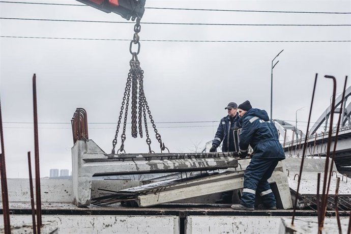 Dos operarios cargan losas de cemento para cortar la carretera, a 2 de marzo de 2022, en Kiev (Ucrania).  