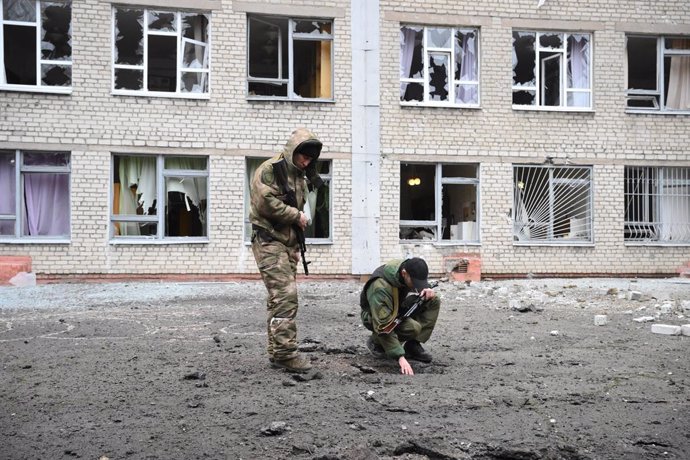 Russian servicemen inspect the damaged concrete pavement in front of the school, which was also damaged as a result of shelling, on February 25, 2022, in Horlivka, Donetsk, Ukraine. On February 24 Russian President Vladimir Putin announced a military op