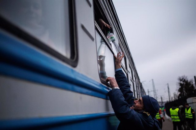 Un hombre entrega una botella de agua a uno de los vagones de la estación de tren de Leópolis