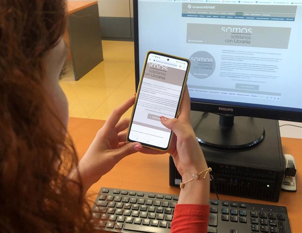 Una usuaria visita a través de su móvil la pestaña 'Somos solidarios con Ucrania', dentro de la web  'www.Hefame.Es'