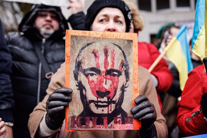 25 February 2022, Slovenia, Ljubljana: A protester holds a placard with a picture of Russian President Putin and the imprint of a bloody hand during a protest against the Russian invasion of Ukraine. Photo: Luka Dakskobler/SOPA Images via ZUMA Press Wir