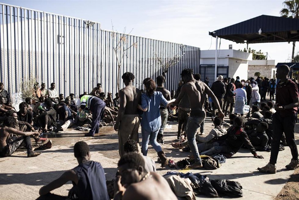Una voluntaria acompaña a dos migrantes, tras saltar la valla de Melilla