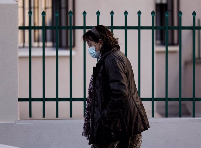 Una mujer camina con mascarilla