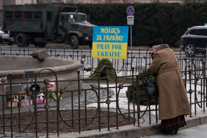 Una mujer mayor observa las flores, que homenajean a los fallecidos por la guerra, junto a un cartel que dice 'Reza por Ucrania''. Ucrania cumple nueve días sumida en un conflicto bélico tras el inicio de los ataques por parte de Rusia. Según las última