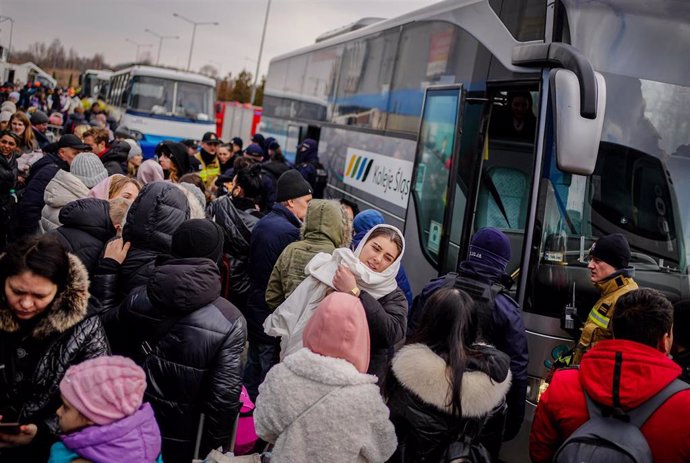 04 March 2022, Poland, Mlyny: Ukrainian refugees wait outside the refugee collection center in Mlyny, a former shopping center just a few kilometers from the Ukrainian-Polish border in Korczowa. Hundreds of thousands are fleeing from Ukraine to the neig