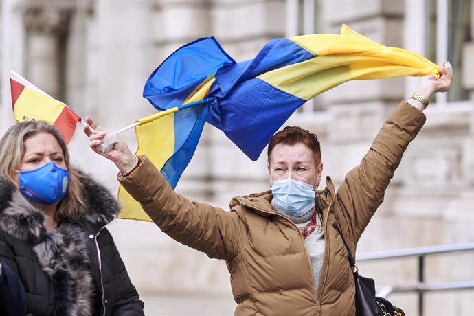 Una mujer con la bandera de Ucrania y de España participa en un minuto de silencio para condenar la guerra.