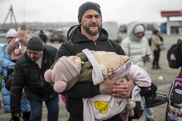 Un hombre con un niño en brazos en el paso fronterizo de Porubne, a 5 de marzo de 2022, en el oeste de Ucrania. Según las últimas informaciones, Ucrania suspendió hoy la evacuación de civiles de Mariupol ante la ruptura del alto el fuego, para abrir cor