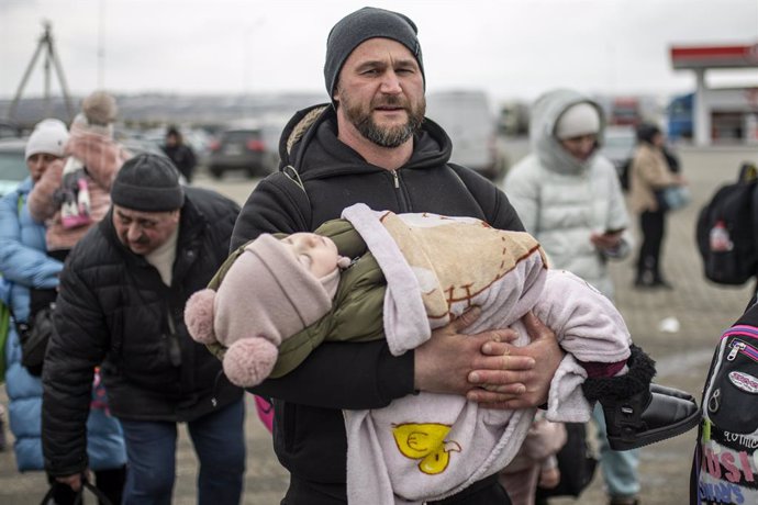 Un home amb un nen en braos en el pas fronterer de Porubne, a 5 de mar de 2022