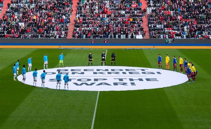 05 March 2022, Bavaria, Munich: The players of Munich and Leverkusen stand together before the match around a banner reading "Stop the War! - Stop the War!" before the German Bundesliga soccer match between Bayern Munich and Bayer Leverkusen at Allianz 