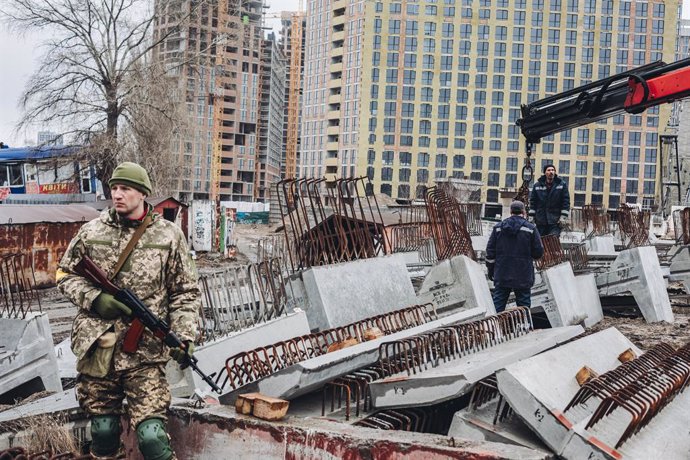 Dos operarios levantan losas de cemento para cortar carreteras, a 2 de marzo de 2022, en Kiev (Ucrania). Las autoridades de Kiev han declarado el toque de queda en la ciudad ante la situación causada por la ofensiva rusa en el país. Más de 2.000 civiles