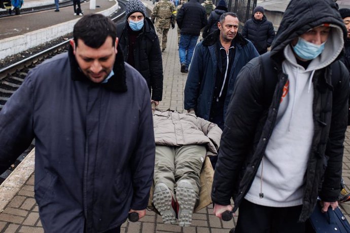Cuatro hombres trasladan a una mujer en camilla que vino de la ciudad de Járkov a 4 de marzo de 2022 en la estación de tren de Lviv (Ucrania). Ucrania cumple nueve días sumida en un conflicto bélico tras el inicio de los ataques por parte de Rusia, el p