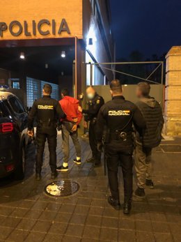 Agentes de Policía Nacional junto a los dos detenidos esposados