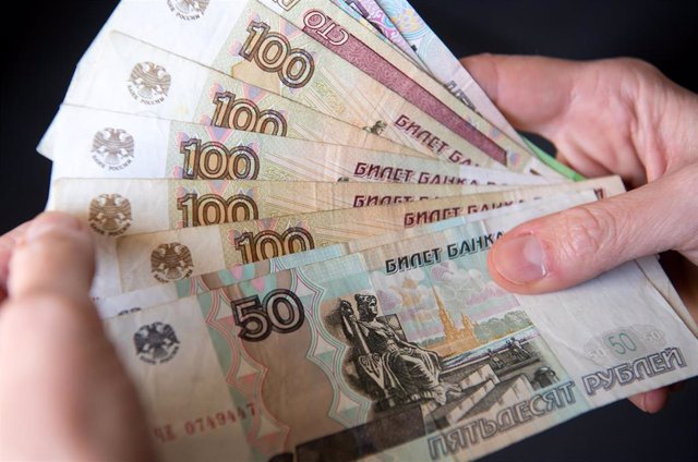 28 February 2022, Bavaria, Munich: A woman holds Russian ruble banknotes in her hands. The European Union put its severe sanctions against the Russian Central Bank into effect on Monday night. Photo: Sven Hoppe/dpa