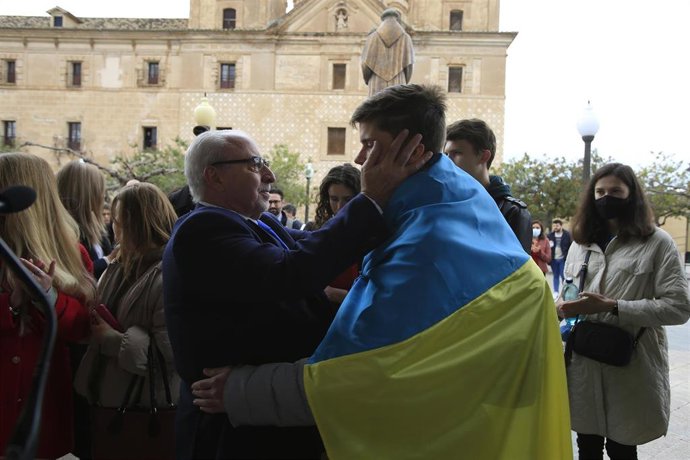 El presidente de la UCAM, José Luis Mendoza, abraza a un estudiante que porta la bandera de Ucrania