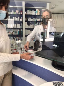Archivo - Una farmacéutica entrega un test a una mujer