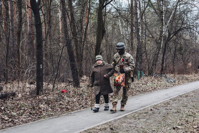 Un soldado ucraniano ayuda a caminar a una anciana bajo el bombardeo en Irpin