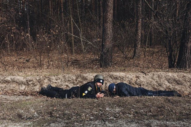 Un policía y un civil se protegen del bombardeo, a 6 de marzo de 2022, en Irpin (Ucrania). 